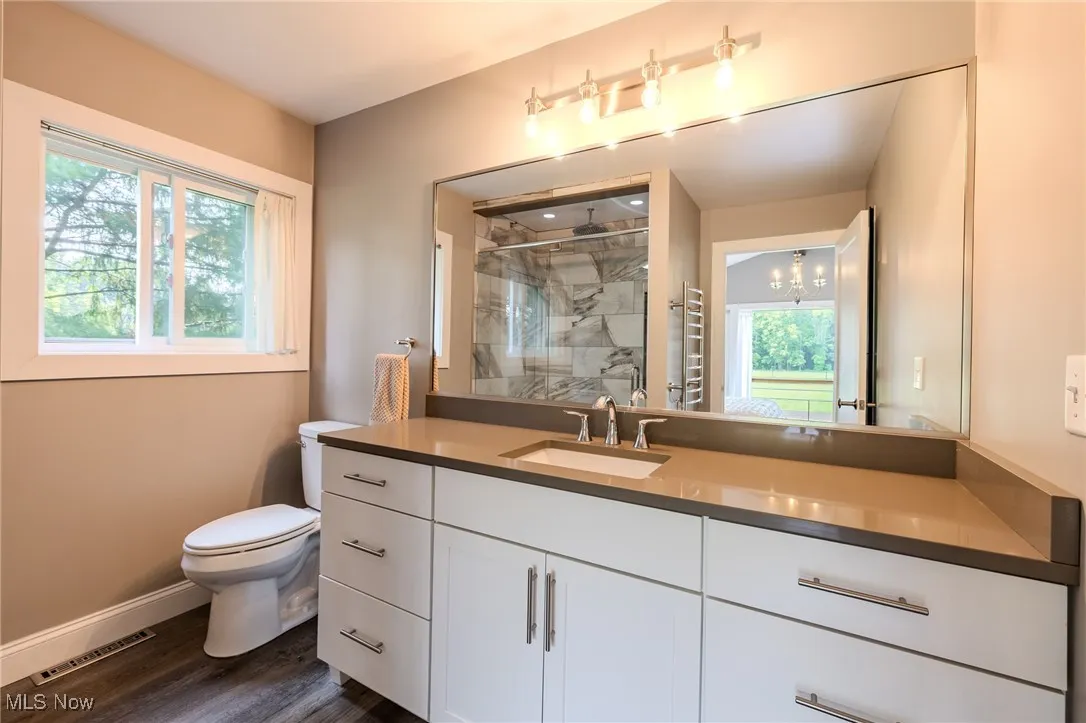 Full bath with toilet, a marble finish shower, vanity, baseboards, and wood finished floors