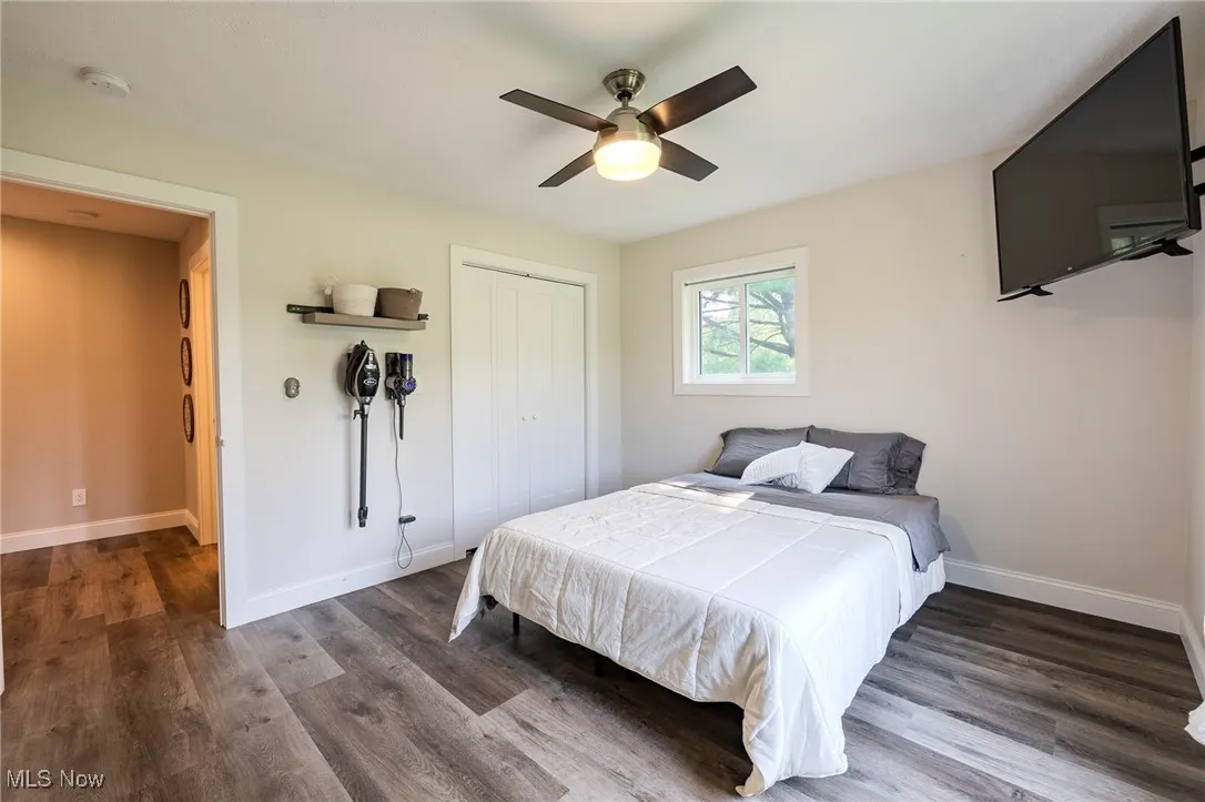 Bedroom featuring a closet, dark wood-style flooring, baseboards, and a ceiling fan