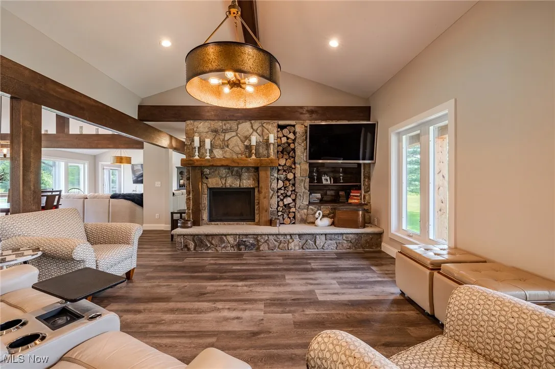 Living area featuring plenty of natural light, wood finished floors, a fireplace, recessed lighting, and high vaulted ceiling