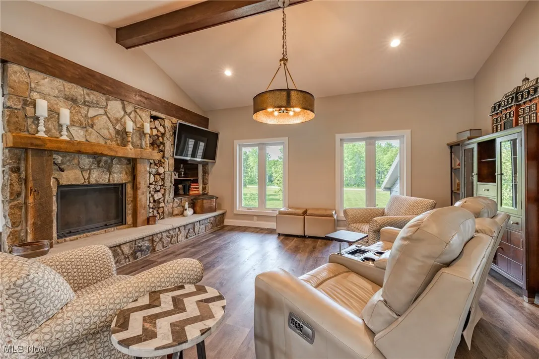 Living area featuring dark wood-style floors, a stone fireplace, and recessed lighting