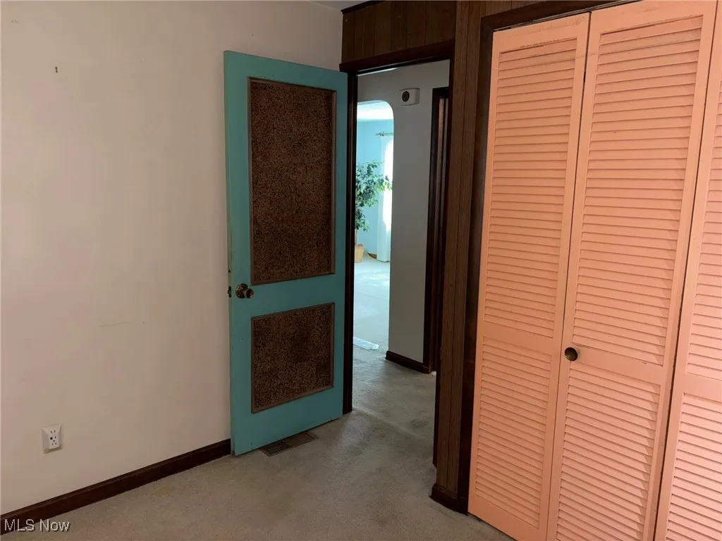 Unfurnished bedroom with light colored carpet, a closet, and baseboards