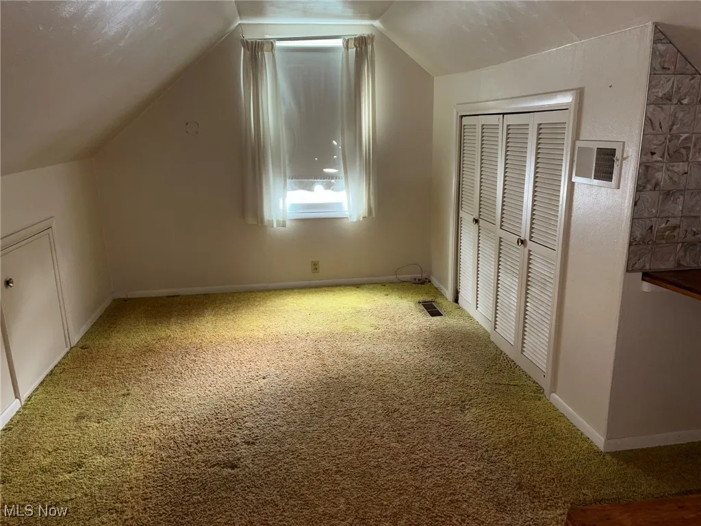 Bonus room featuring carpet, vaulted ceiling, and baseboards