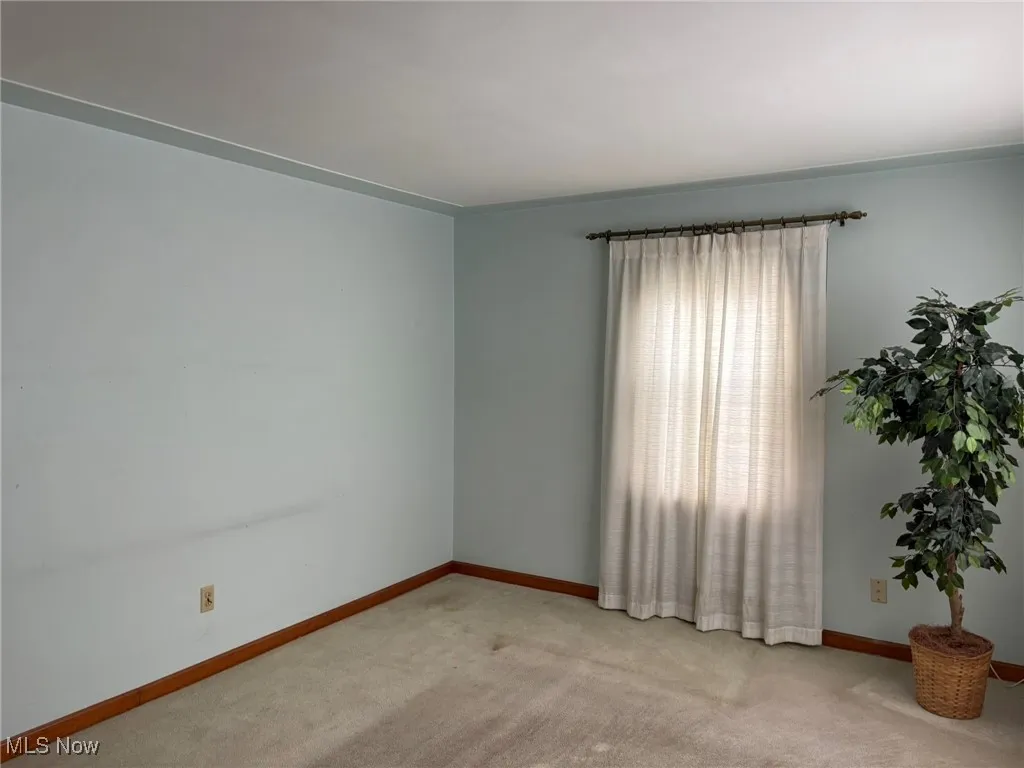 Unfurnished room with light colored carpet and baseboards