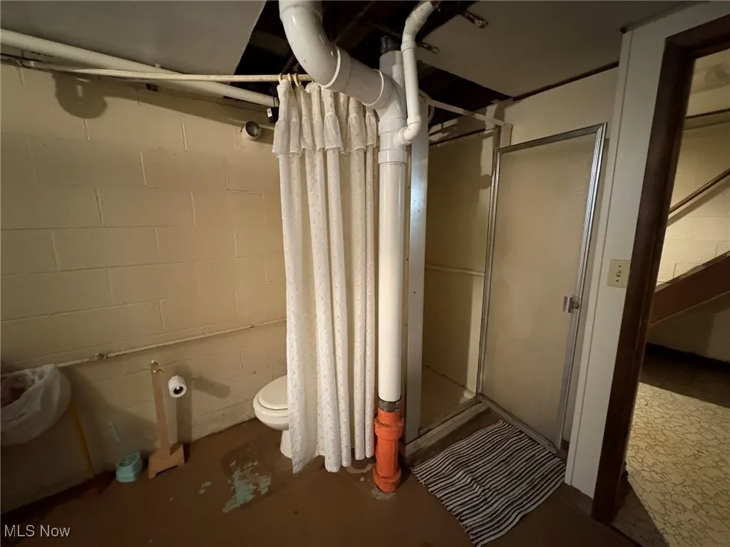 Bathroom with a stall shower, concrete floors, and toilet