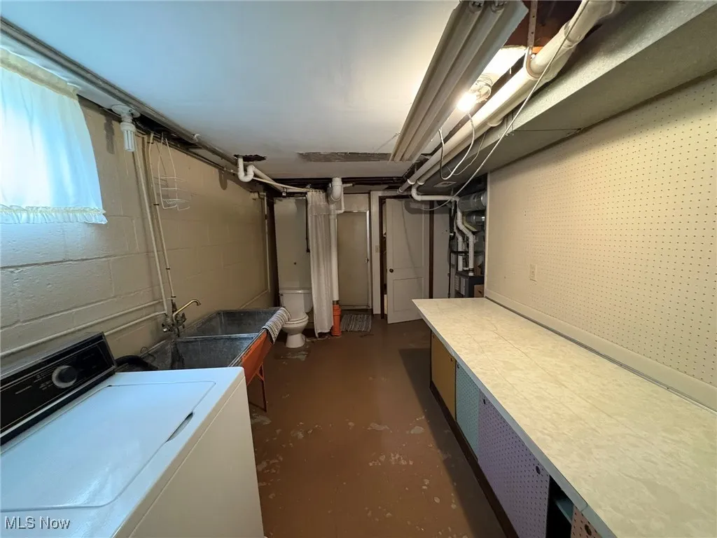 Below grade area with washer / dryer, a sink, and concrete block wall