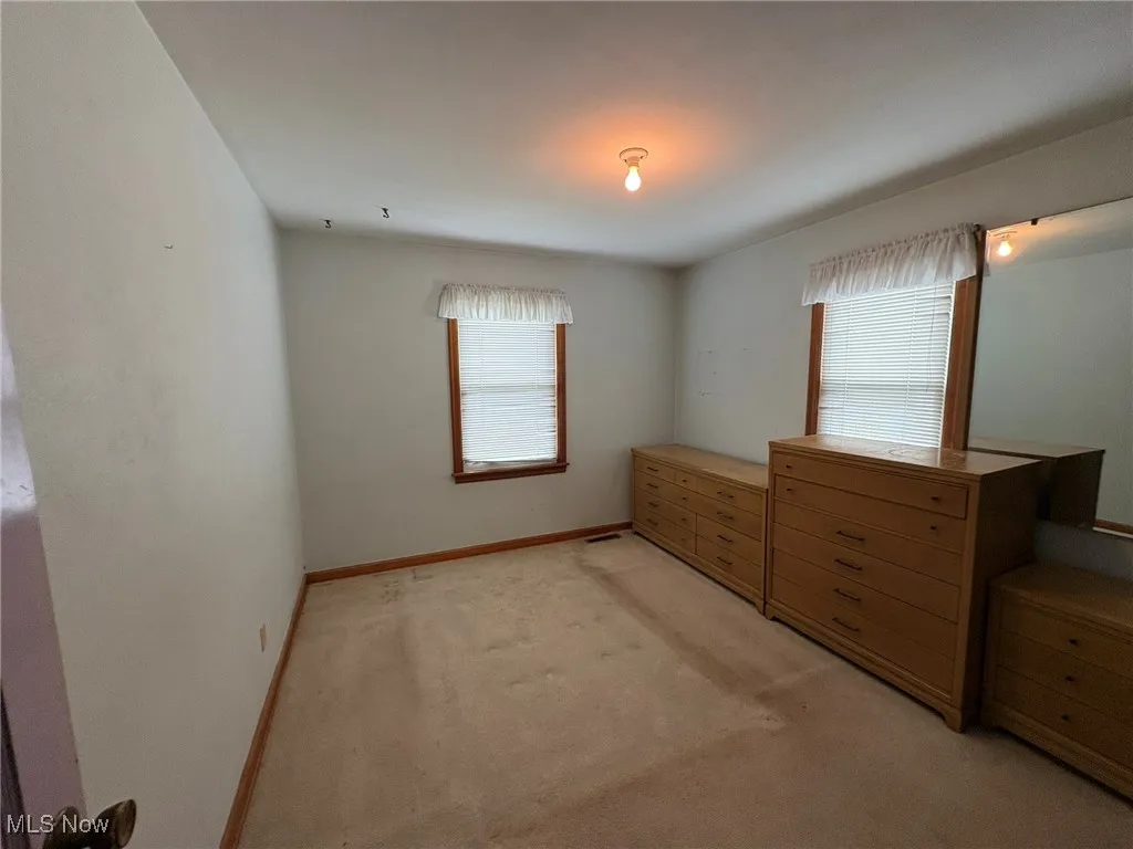 Unfurnished bedroom featuring light carpet and baseboards