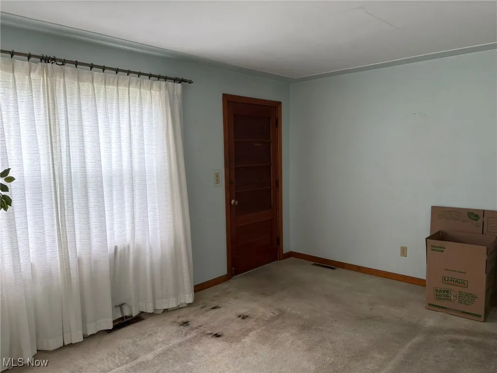 Unfurnished room with light colored carpet and baseboards