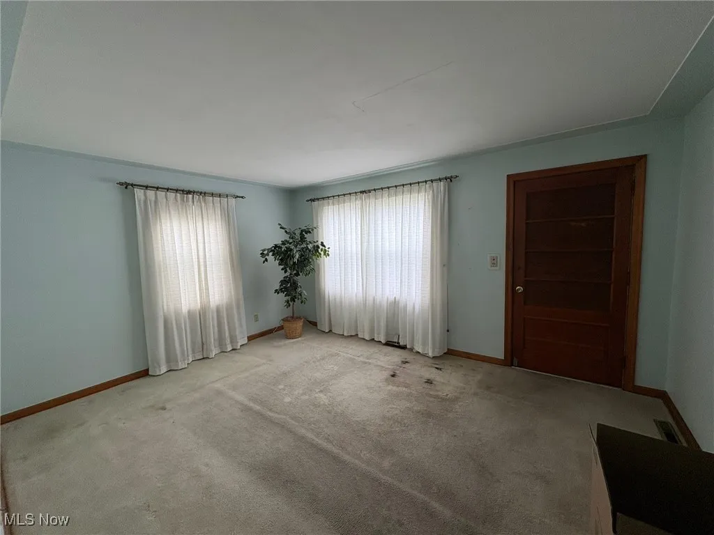 Unfurnished room featuring healthy amount of natural light, baseboards, and light carpet
