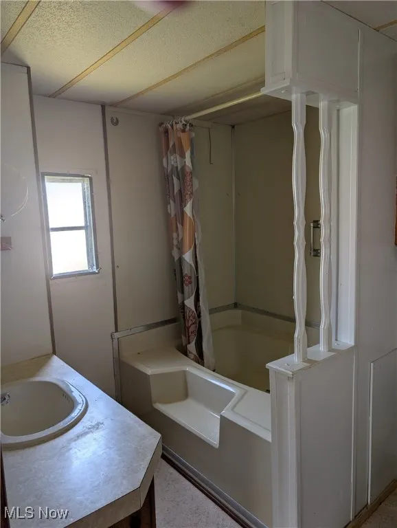 Bathroom with shower / bath combination with curtain and vanity