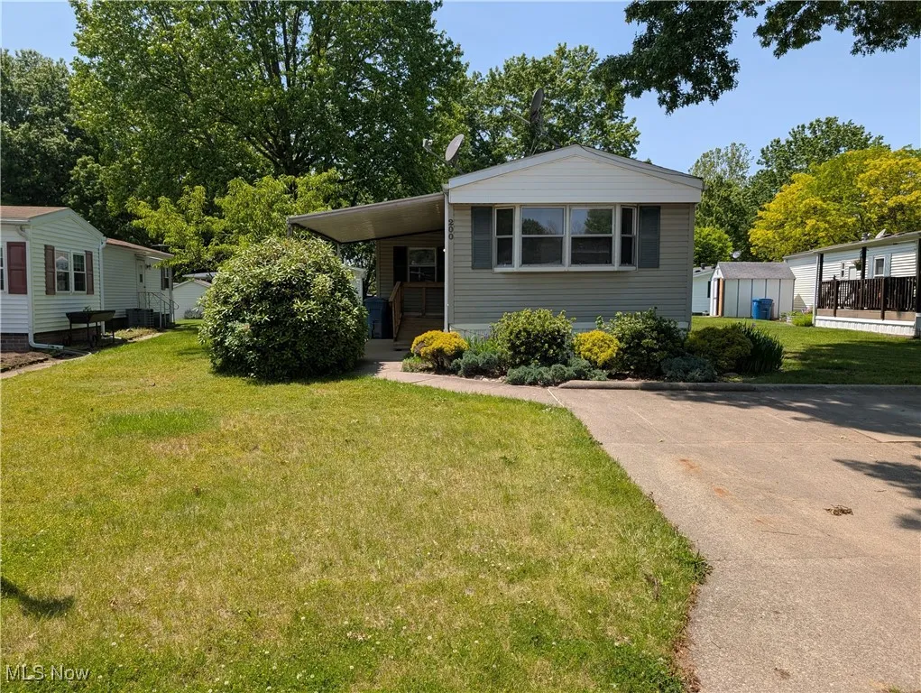 Manufactured / mobile home with a front lawn and a carport