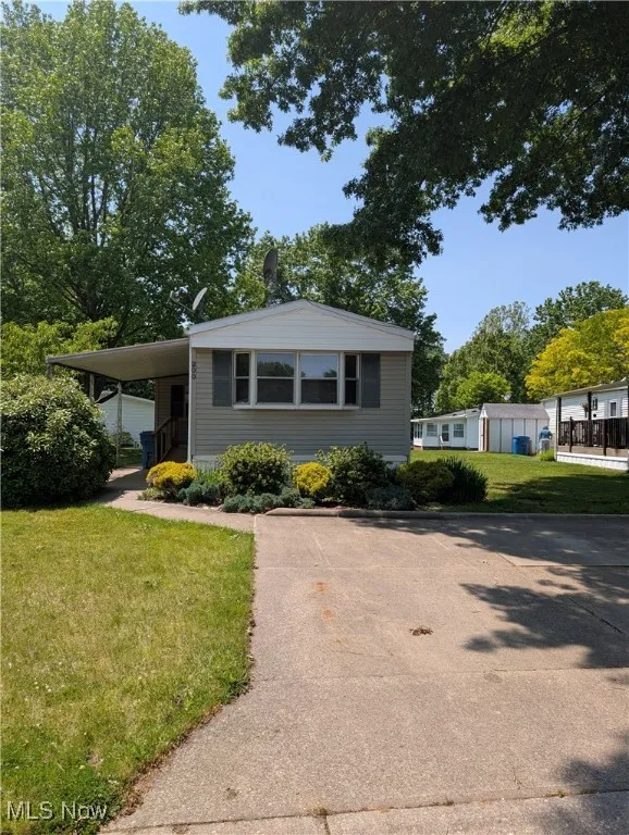 Manufactured / mobile home with a front lawn, driveway, and an attached carport