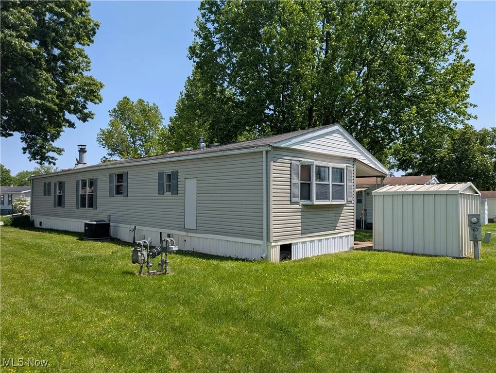 Rear view of house with central AC unit and a yard