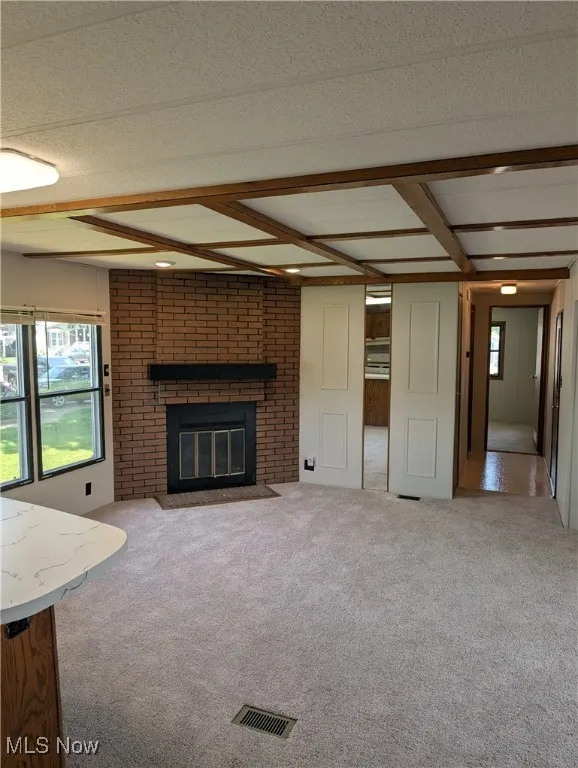 Unfurnished living room featuring carpet floors and a fireplace