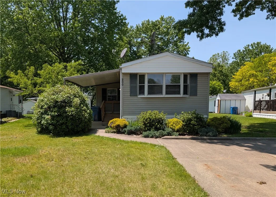 View of front of property with a front yard, a carport, and cooling unit