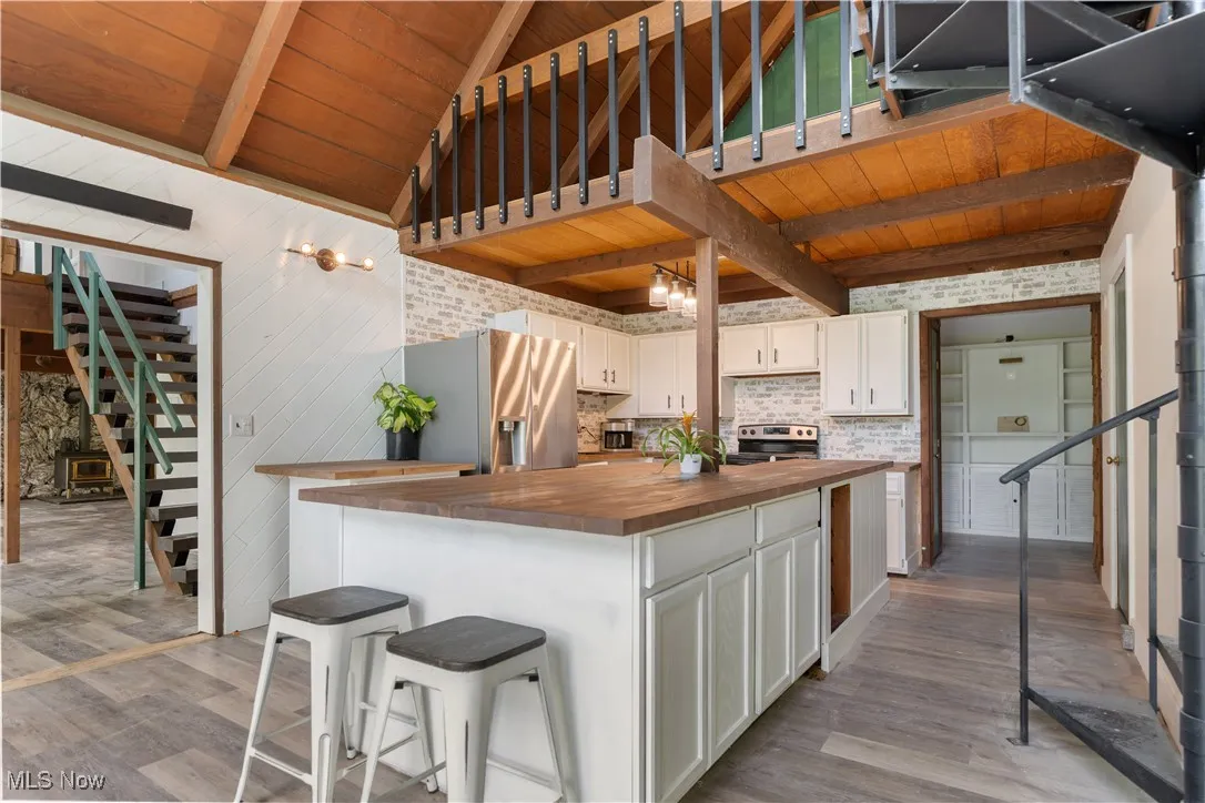 Kitchen featuring wooden counters, appliances with stainless steel finishes, dark wood-style flooring, wood ceiling, and white cabinets