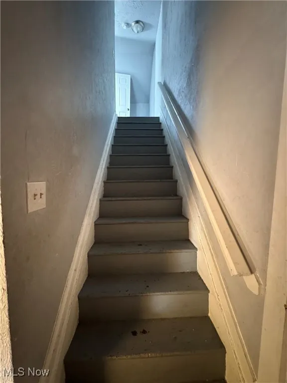 Stairs featuring a textured wall