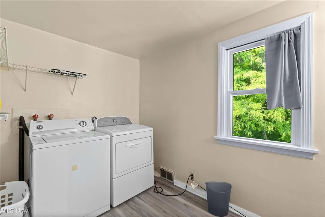 Laundry area featuring washing machine and clothes dryer, light wood-style flooring, and baseboards