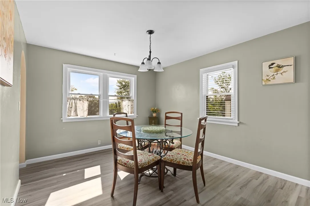 Dining space with a chandelier, wood finished floors, and baseboards
