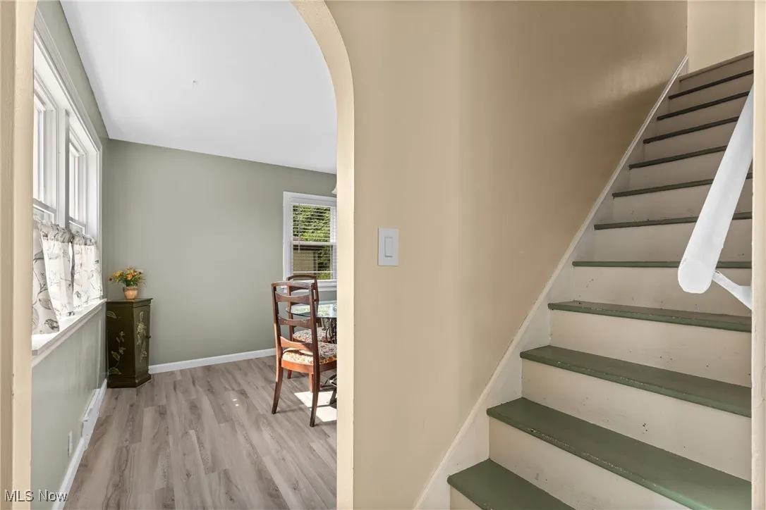 Staircase featuring arched walkways, wood finished floors, and baseboards