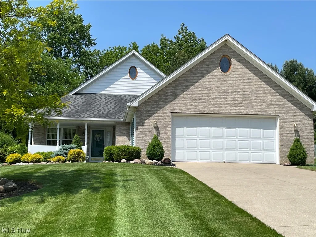Traditional-style home with brick siding, an attached garage, a front yard, concrete driveway, and a shingled roof