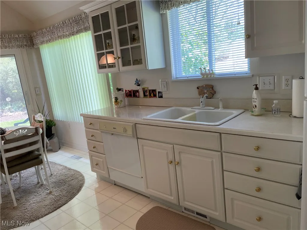 Kitchen with plenty of natural light, glass insert cabinets, and light tile patterned floors