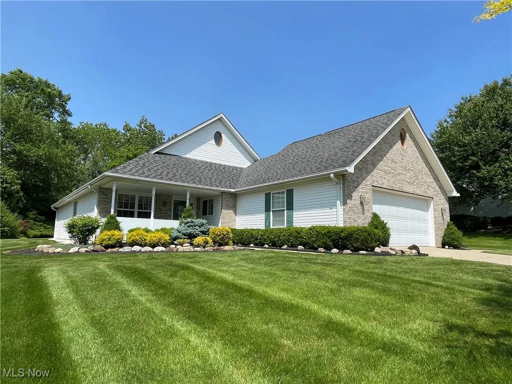 View of front of home featuring an attached garage, a front lawn, brick siding, and driveway