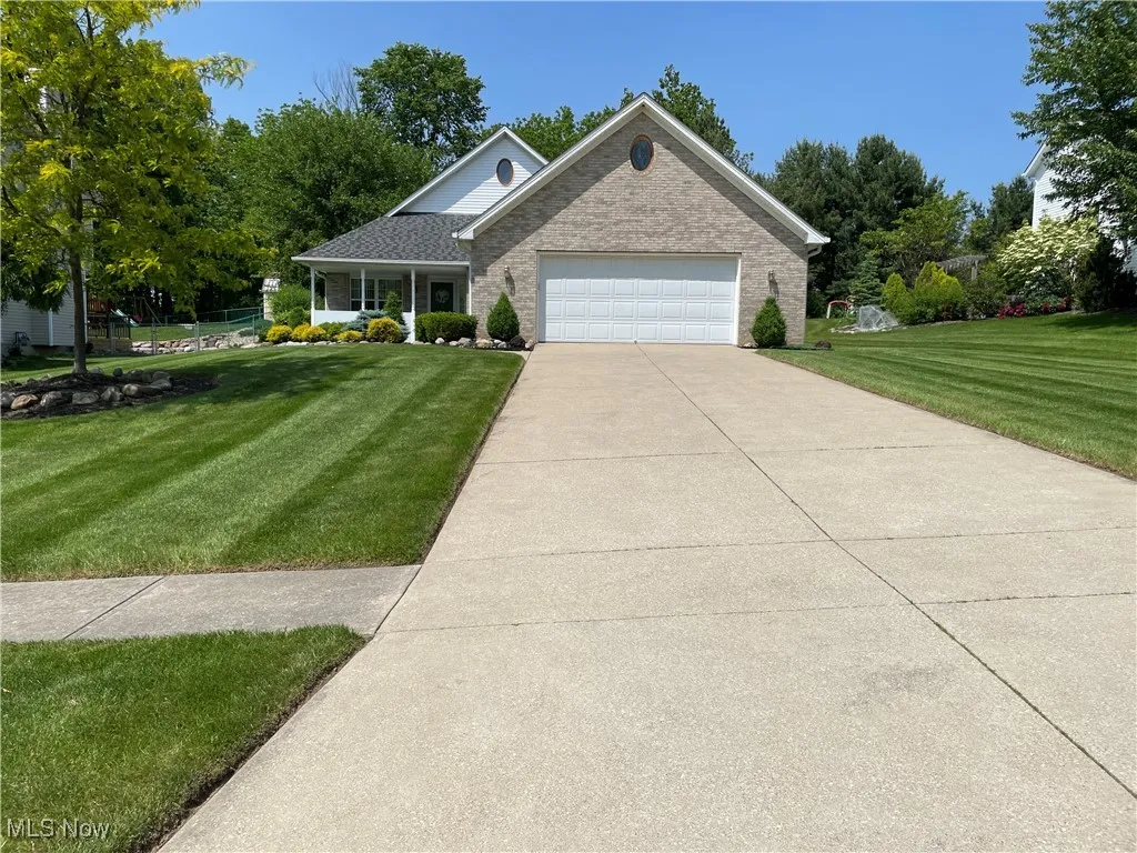 View of front of property with a front yard, a garage, brick siding, and concrete driveway
