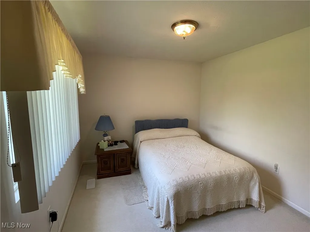Bedroom featuring light carpet and baseboards