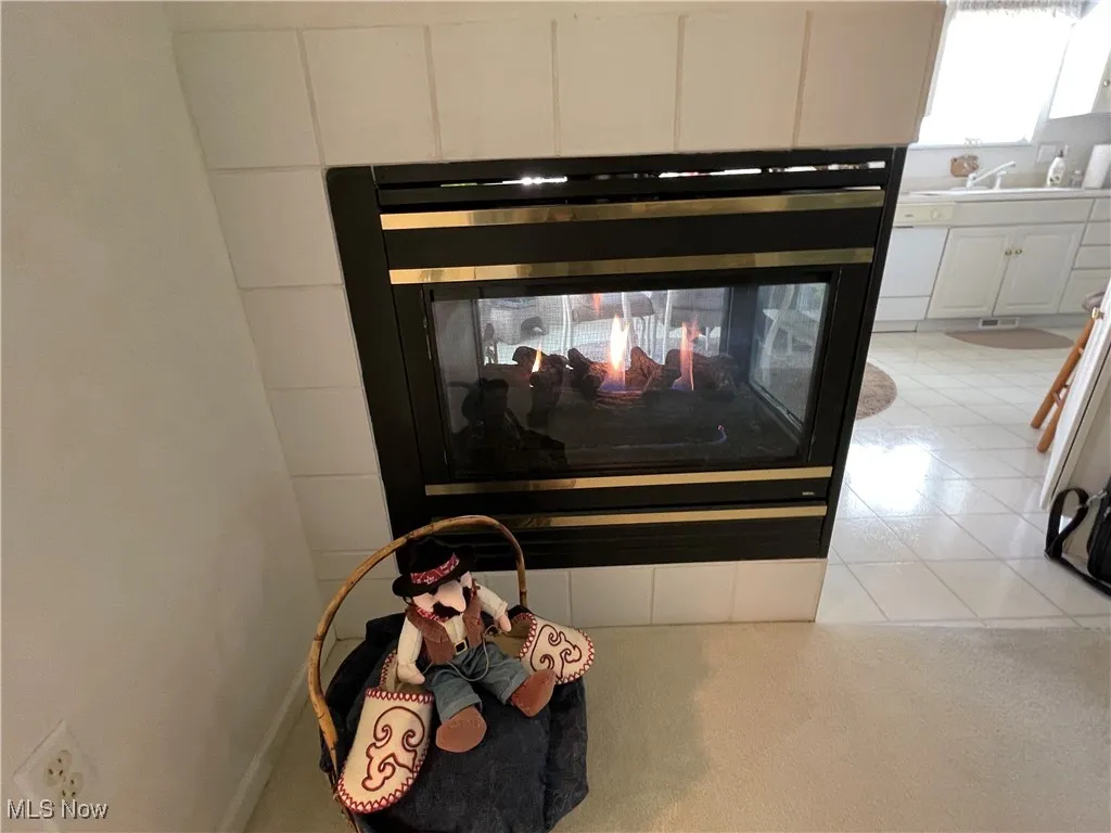 A 3 sided gas fireplace is seen by the dining area, living room and kitchen.