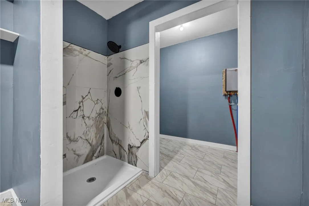 Bathroom with a marble 
 like finish shower and marble finish floors