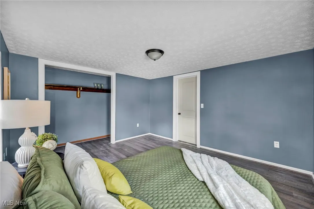 Bedroom featuring wood finished floors, baseboards, a closet, and a textured ceiling
