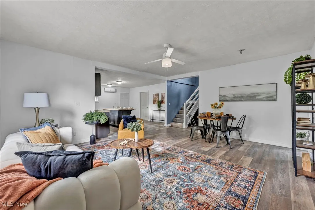 Living area with stairway, ceiling fan, wood finished floors, baseboards, and a textured ceiling
