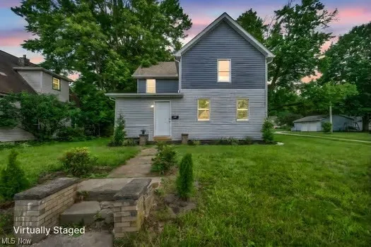 Back of property at dusk featuring a lawn