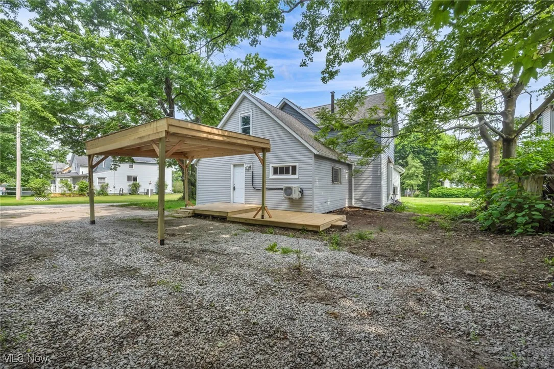 rear view of house with a deck, a detached carport, and a shingled roof