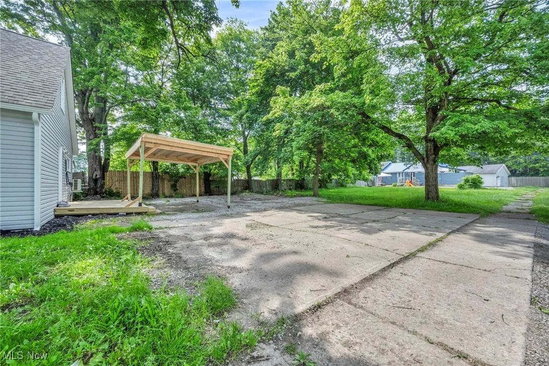View of patio with a carport, concrete driveway, and a deck
