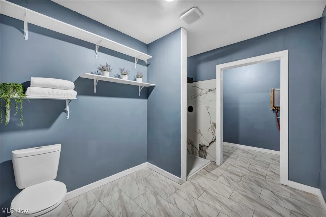 Bathroom with marble finish floors, a marble finish shower, toilet, and baseboards