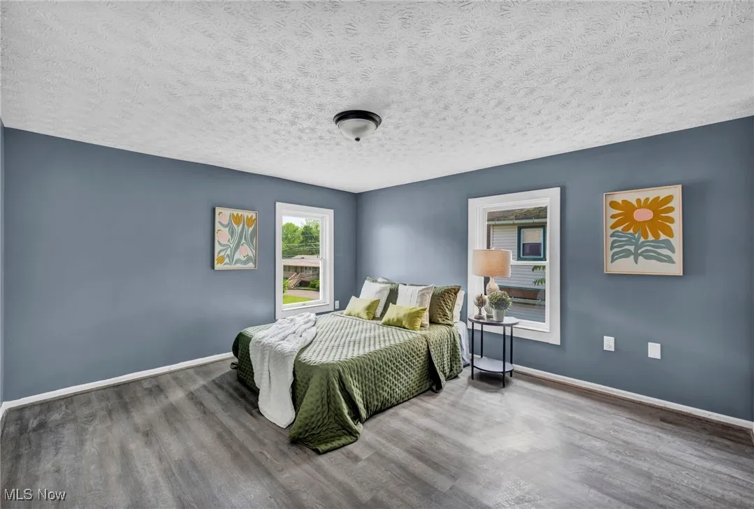 Bedroom with wood finished floors, baseboards, and a textured ceiling