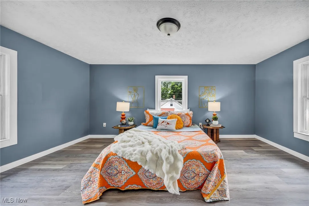 Bedroom featuring wood finished floors, baseboards, and a textured ceiling