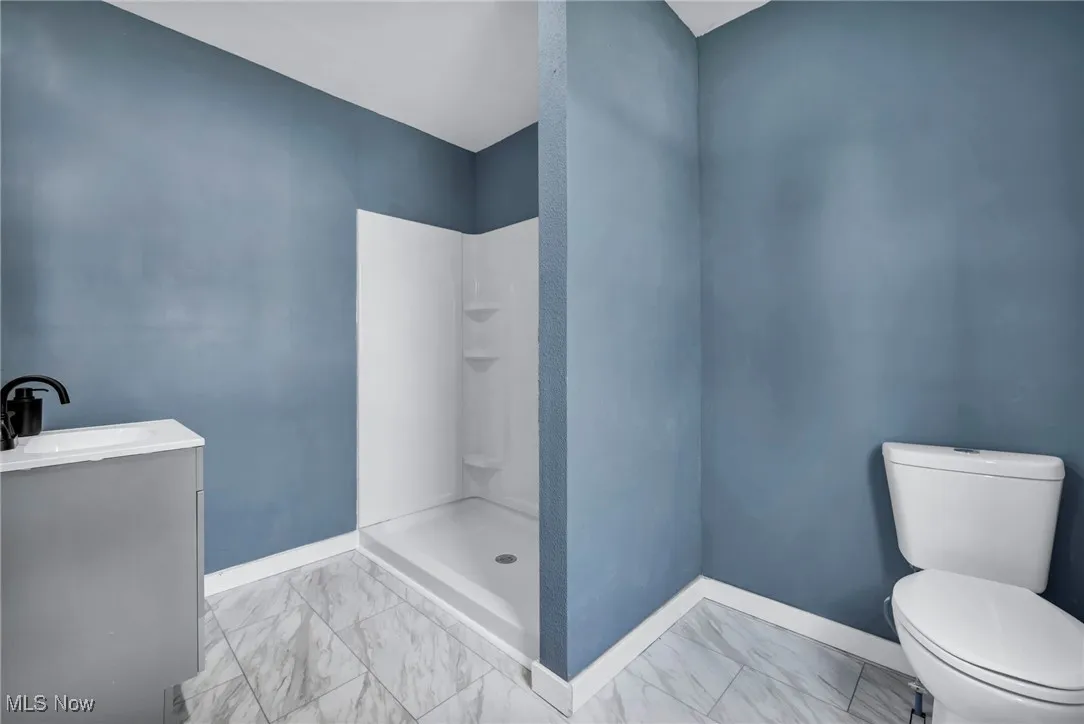 Full bath with toilet, marble finish floors, a shower, baseboards, and vanity