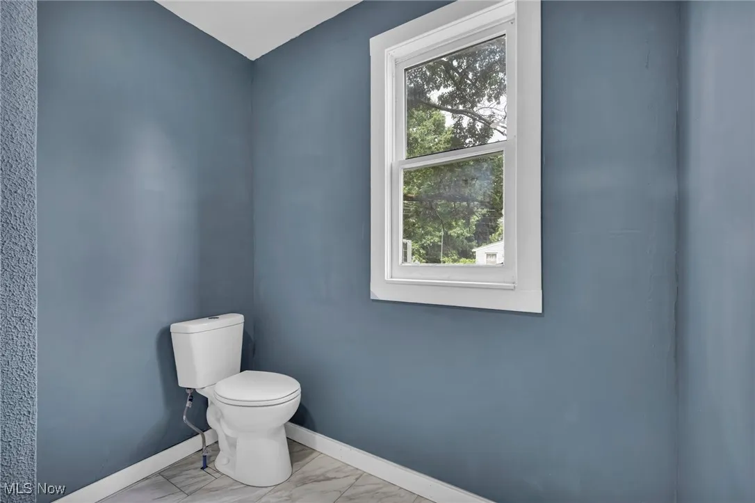 full bath featuring toilet, baseboards, and marble look tile flooring