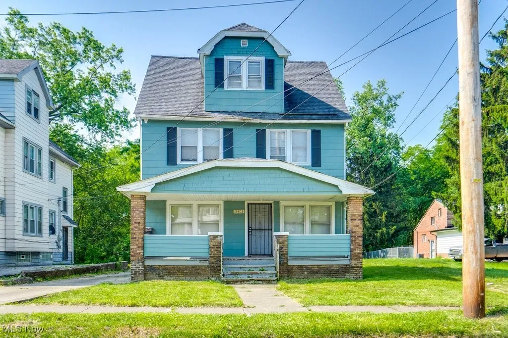Traditional style home with covered porch, a front yard, and a shingled roof