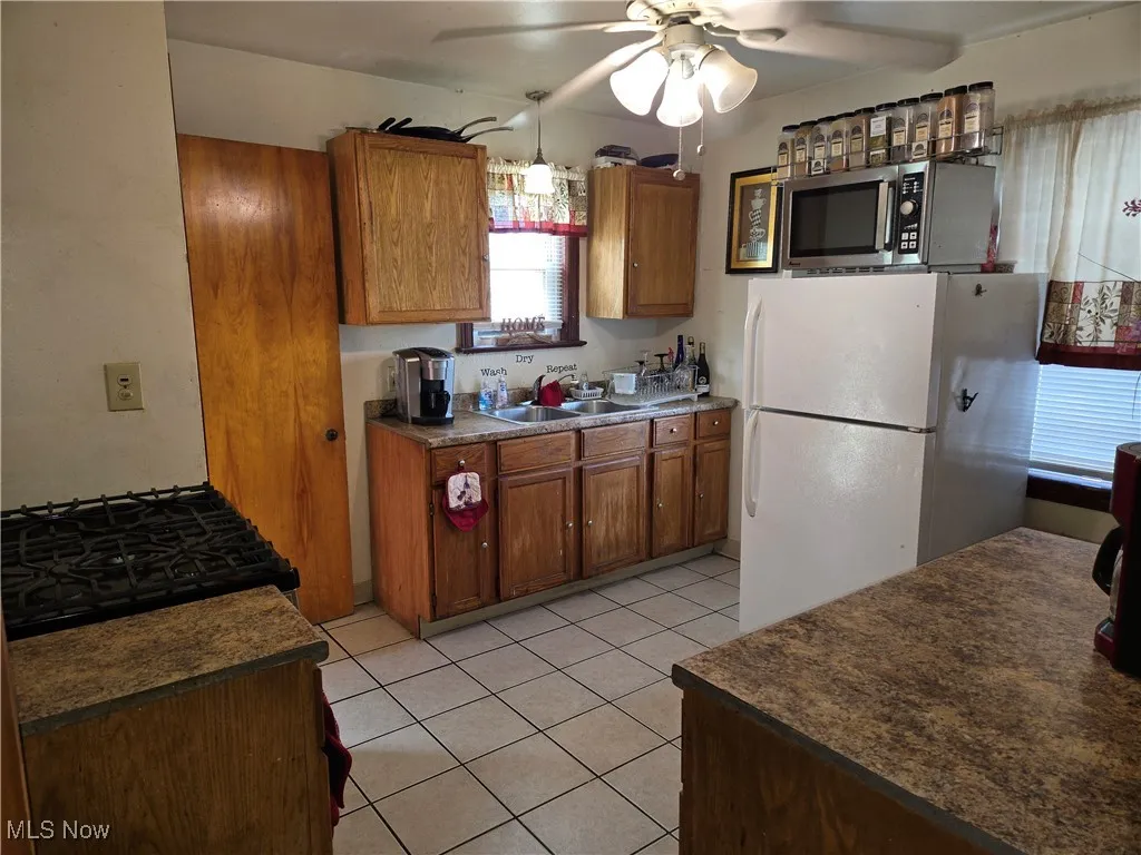 Kitchen with stainless steel microwave, freestanding refrigerator, a sink, and brown cabinets