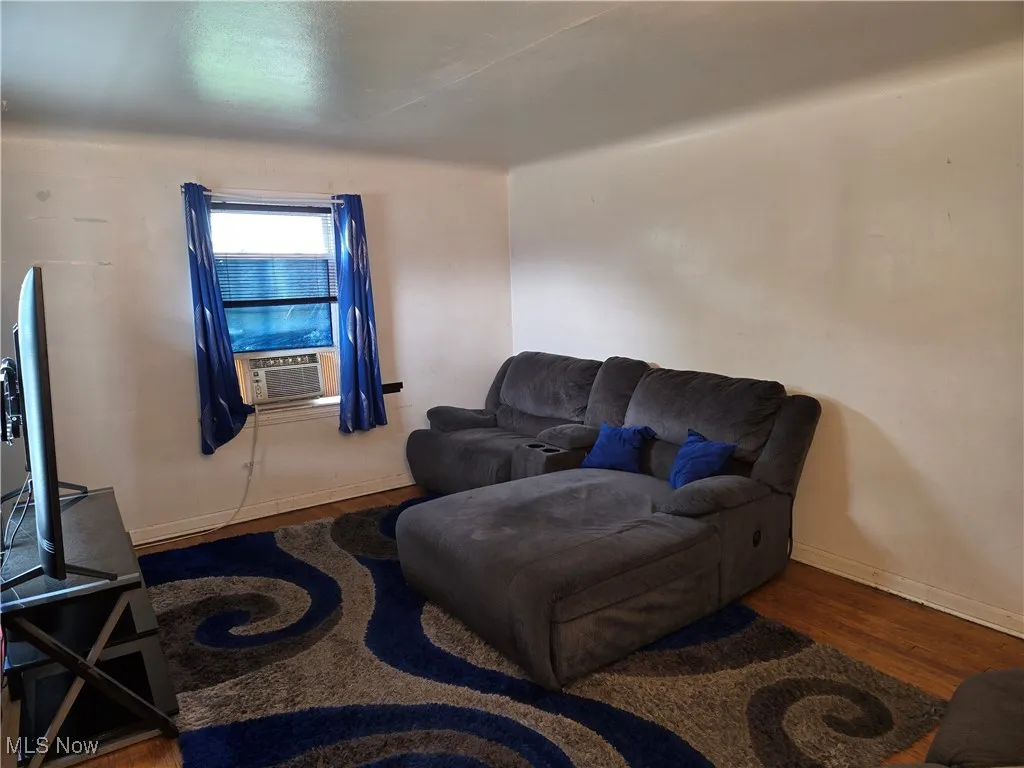 Living room featuring wood finished floors, cooling unit, and baseboards
