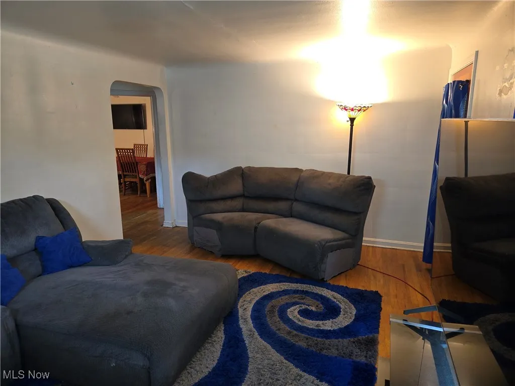 Living room featuring arched walkways, wood finished floors, and baseboards
