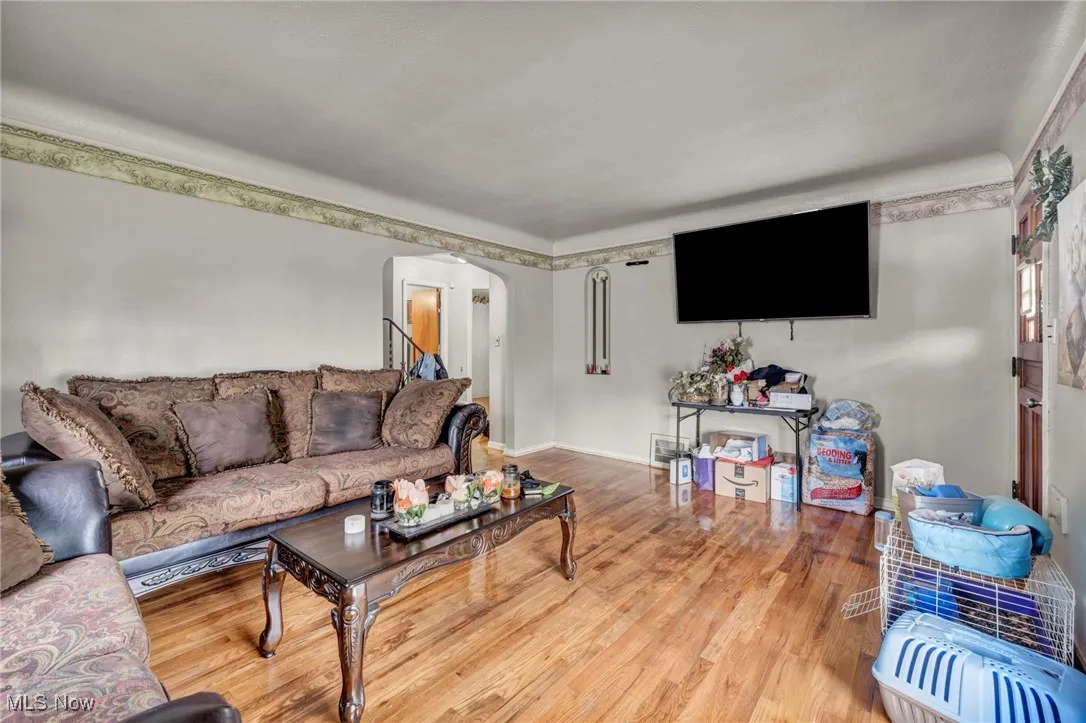 Living area with arched walkways, wood finished floors, and baseboards