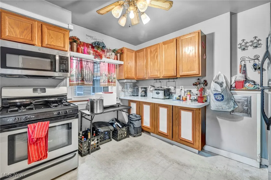 Kitchen with stainless steel appliances, ceiling fan, light countertops, and light flooring