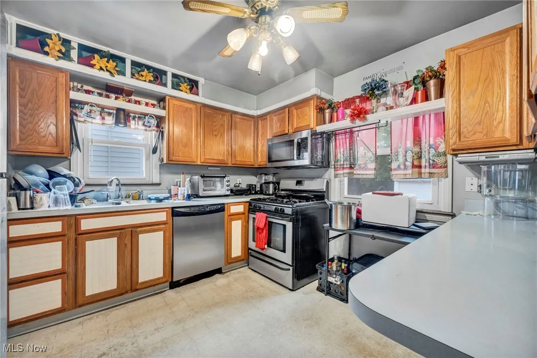 Kitchen featuring stainless steel appliances, healthy amount of natural light, light countertops, and open shelves
