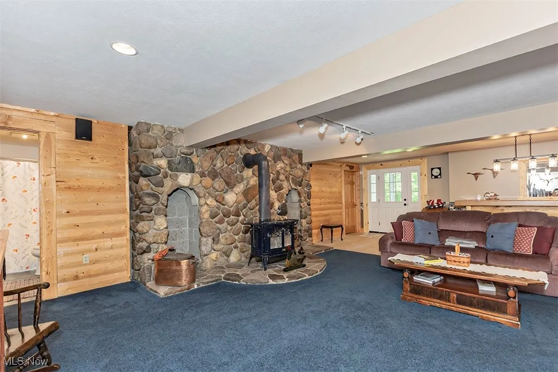 Woodburning stove is inset into stone wall with log storage niches. Pine log accent wall. Door to the far left leads to full bath.