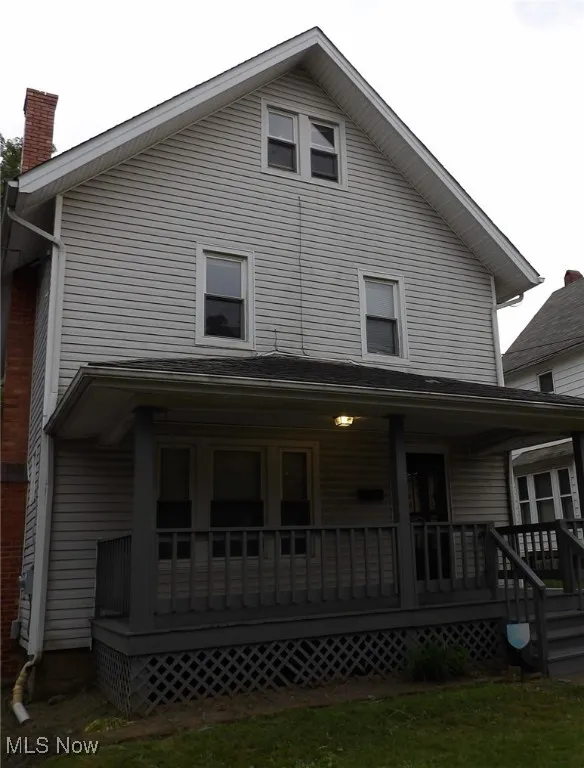 Back of property with covered porch and a chimney