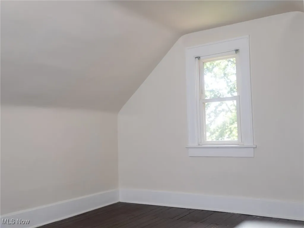 Additional living space with vaulted ceiling and dark wood-style flooring